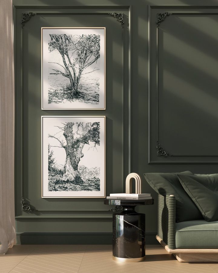 Two tree drawings hung one above the other on a green paneled wall